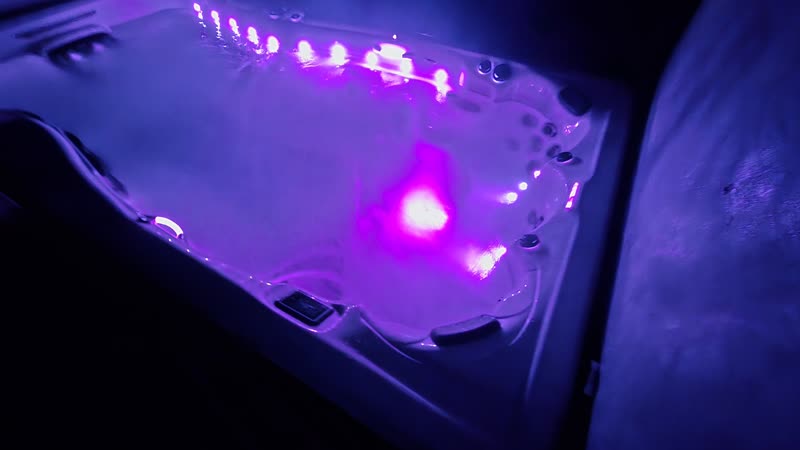 Swim spa lit magenta at night, lights low